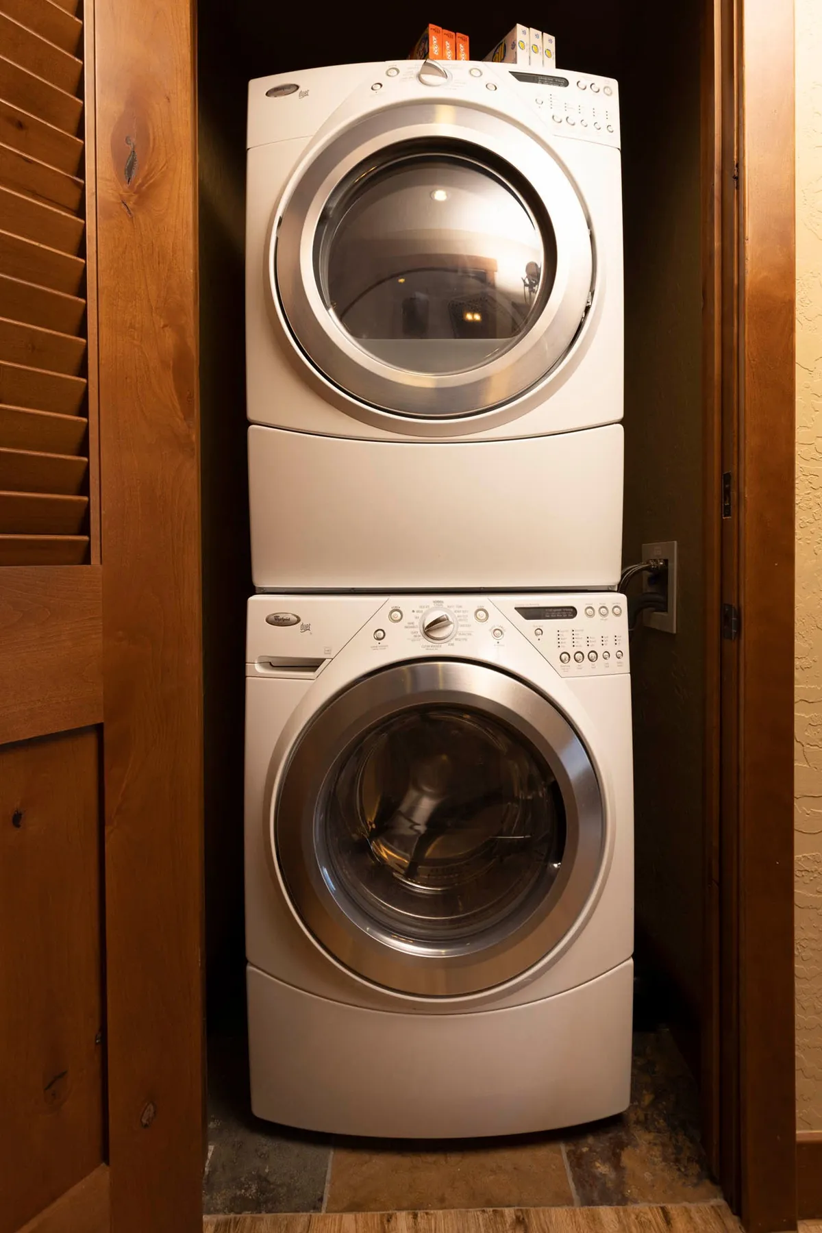 A stacked washer and dryer tucked into a space with wooden cabinetry, showcasing modern appliances and efficient use of space.